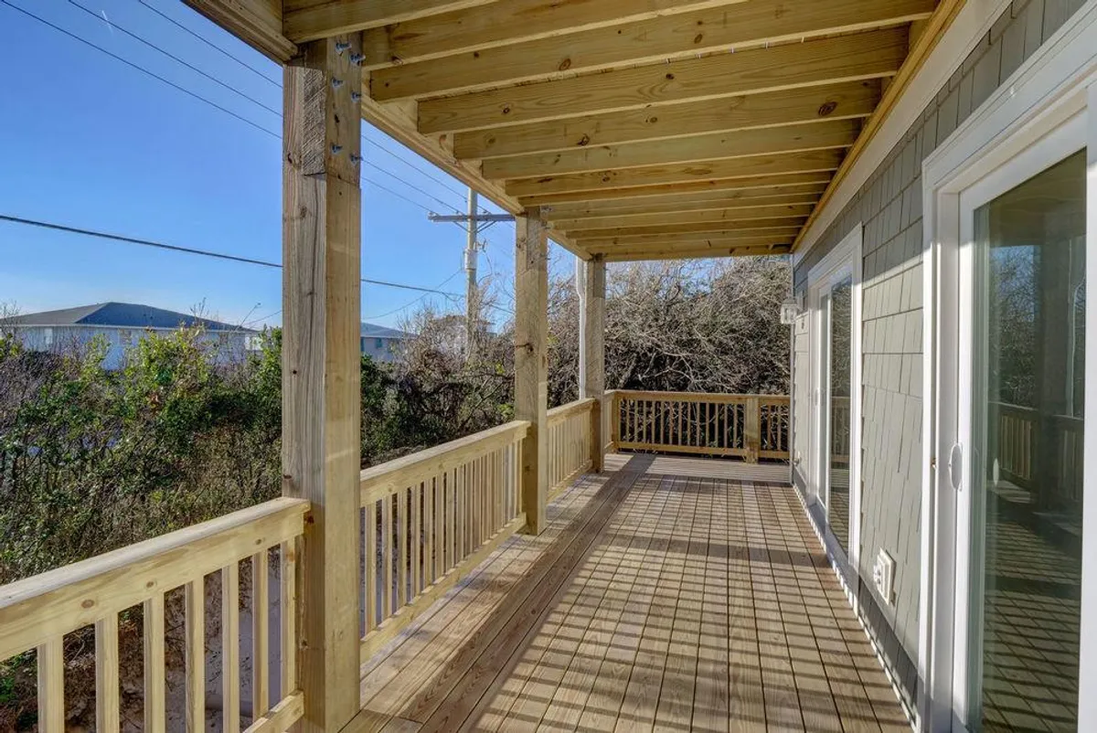 A wooden deck surrounded by greenery and an open sky, inviting gatherings for morning coffee or evening cocktails. The tranquil setting suggests a place to relax with friends before heading out or winding down after exploring local nightlife.