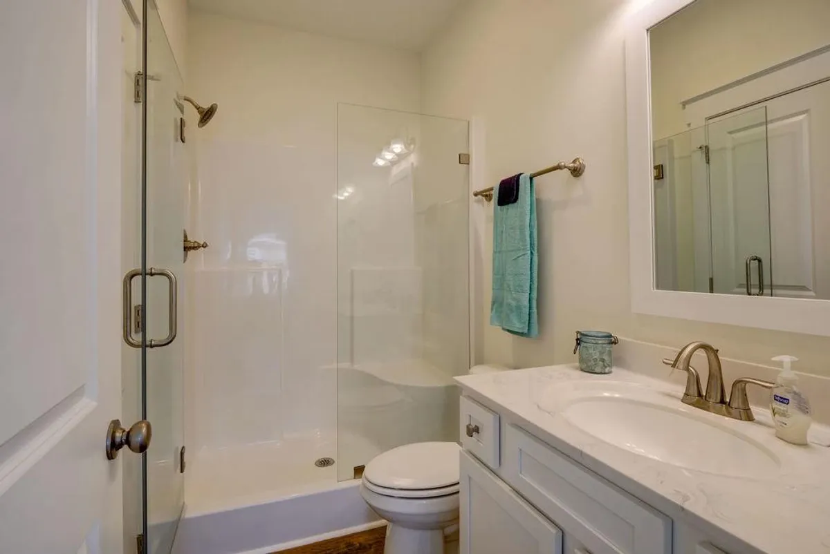 A bright, fresh bathroom featuring a glass-enclosed walk-in shower, a double sink vanity, and sleek modern fixtures. The design is clean and contemporary, with ample space for comfortable morning or evening routines.