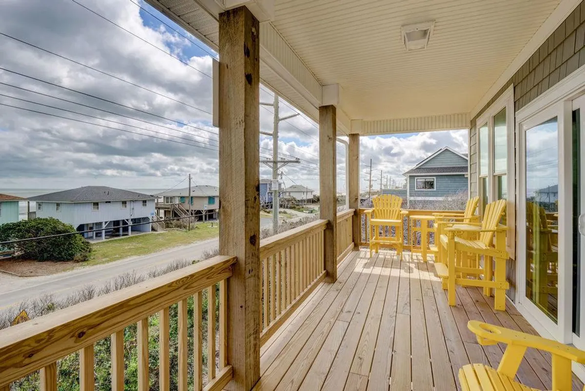 A welcoming deck scene features a pair of cheerful yellow chairs set on a wooden deck overlooking neighboring houses, suggesting a perfect spot for morning coffee or evening relaxation after a day of exploration. The ambiance feels both private and connected to the wider neighborhood.