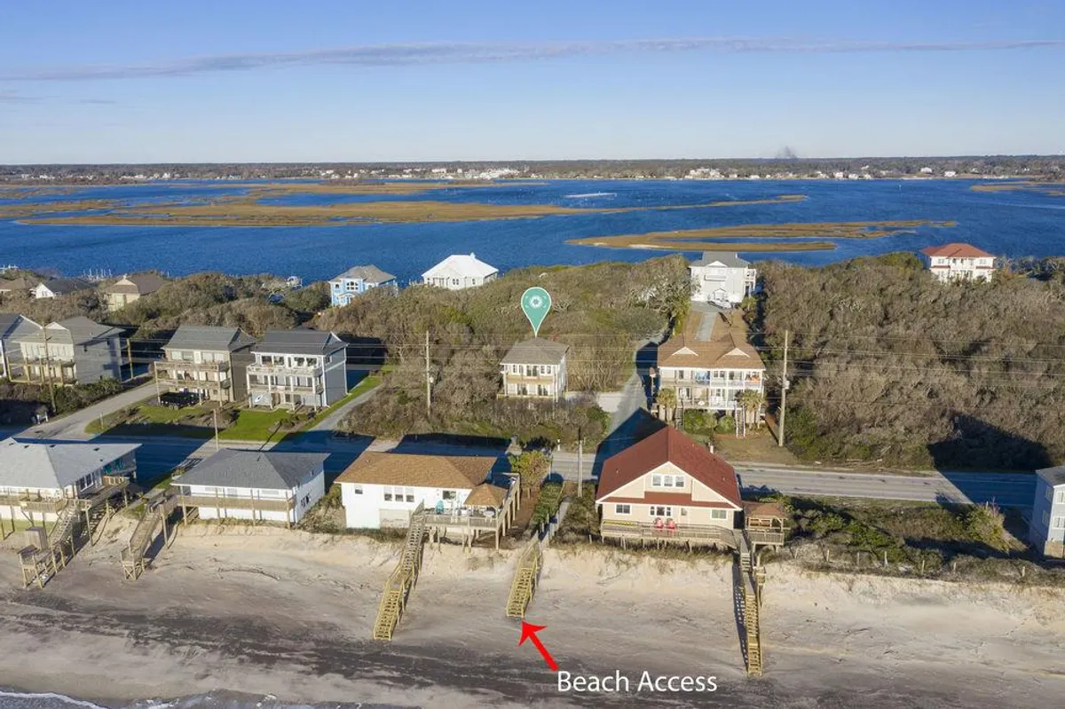 A bright exterior shot features a charming beach access point leading to the waterway, with cozy surrounding houses and a clear path for families to reach the shoreline. The inviting landscape hints at a relaxing community vibe ideal for family gatherings or spontaneous adventures.